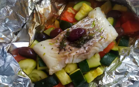 Zeleninu nakrájíme na větší kousky. Připravíme si alobal nebo pečicí papír na dva balíčky.  Nakrájenou zeleninu naskládáme do jehich středu. Osolíme, opepříme. Navrch položíme tresku. Posypeme utřeným česnekem, tymiánem, osolíme a opepříme. Nakonec zastříkneme olivovým olejem a citronovou šťávou. Zabalíme do pevného balíčku, aby šťáva nevytekla. U alobalu okraje založíme, v případě pečicího papíru pevně zavážeme.
Troubu předehřejeme na 200°C a pečeme 12 minut.
Nakonec v horkém pokrmu necháme rozpustit oříšek másla.