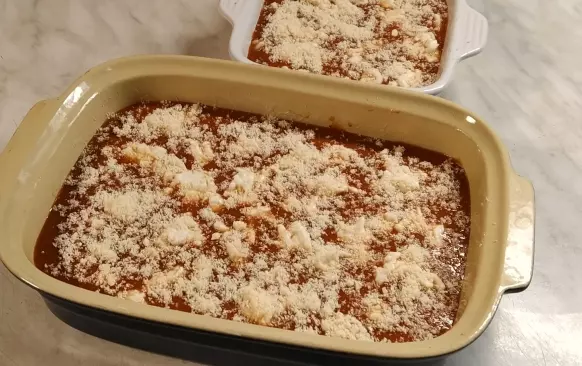 Trubičky zalijeme rajčatovou omáčkou (část omáčky si můžeme nechat na servírování), poklademe nastrouhanou mozzarellou a posypeme nastrouhaným sýrem parmezánového typu.