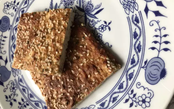 Květák rozebereme na růžičky a rozmixujeme nebo nastrouháme na drobenku.
Přidáme mouku, vejce, sůl a koření a důkladně promícháme, až vznikne polotekutá hmota. 
Tu rozprostřeme na plech s pečícím papírem a posypeme semínky.
Pečeme v předem vyřáté troubě na 200° přibližně 25 minut, než zezlátne a zpevní se.
Po vychladnutí nakrájíme na čtverečky a zdobíme dle libosti.