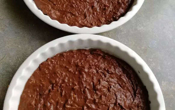 Čokoládu s máslem rozpustíme ve vodní lázni, přidáme sladidlo a žloutky. Postupně přimícháme mandlovou mouku, smetanu a slunečnicová semínka. Vyšleháme bílky do tuhého sněhu, který přimícháme jako poslední.  
Připravíme si 2 stějně velké formy na dort či na koláč v průměru 20- 25 cm, které vysteleme pečícím papírem a těsto do nich rozetřeme. 
Pečeme 15 minut na 170 ° C.