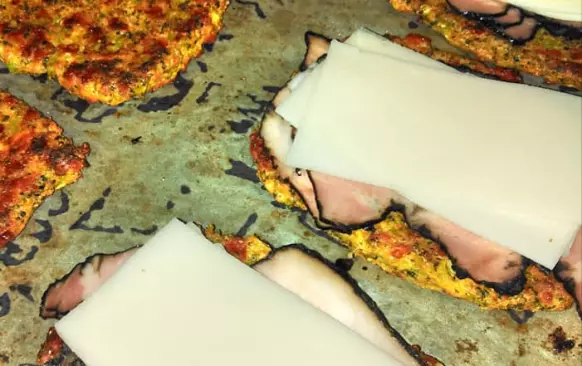 1 syrovou brokolici nasekat najemno, přidat 2 celá vejce, velkou hrst strouhaného sýra, česnek, koření dle chuti. Mokrou rukou udělat placičky nebo čtverce, dát na plech s pečícím papírem potřený olivovým olejem, péct na 180st 10 minut, pak obrátit, obložit, přiklopit prázdným čtvercem(placičkou) trochu přimáčknout, dopéct ještě 10minut