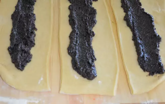 Tyto klobásy pak narovnáme do pečící formy za sebe do tvaru spirály. Necháváme mezi nimi mezery, aby bylo kam narovnat napůlené švestky. viz obr.  Švestky posypeme cukrem krystalem. Pečeme do zlatohněda, pět minut před dopečením vytáhneme a potřeme rozpuštěným máslem.