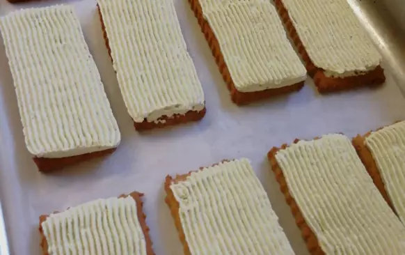 Rozpustíme si čokoládu, kokosový olej a smetanu.

Do čokolády namáčíme postupně sušenky krémem dolů.