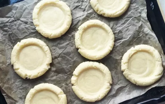 takto necháme ještě 20 minut kynout na teplém místě
vykynuté kuličky potom rozmáčkneme uprostřed hrnečkem (vznikne tak důlek, který budeme plnit)